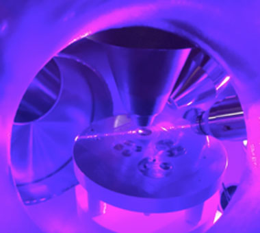 Figure 2. the view into the lion mass spectrometer sample chamber, showing several samples on the stage. the bright stripe across the stage is from the resonance ionization lasers passing just above the natural uranium metal sample.